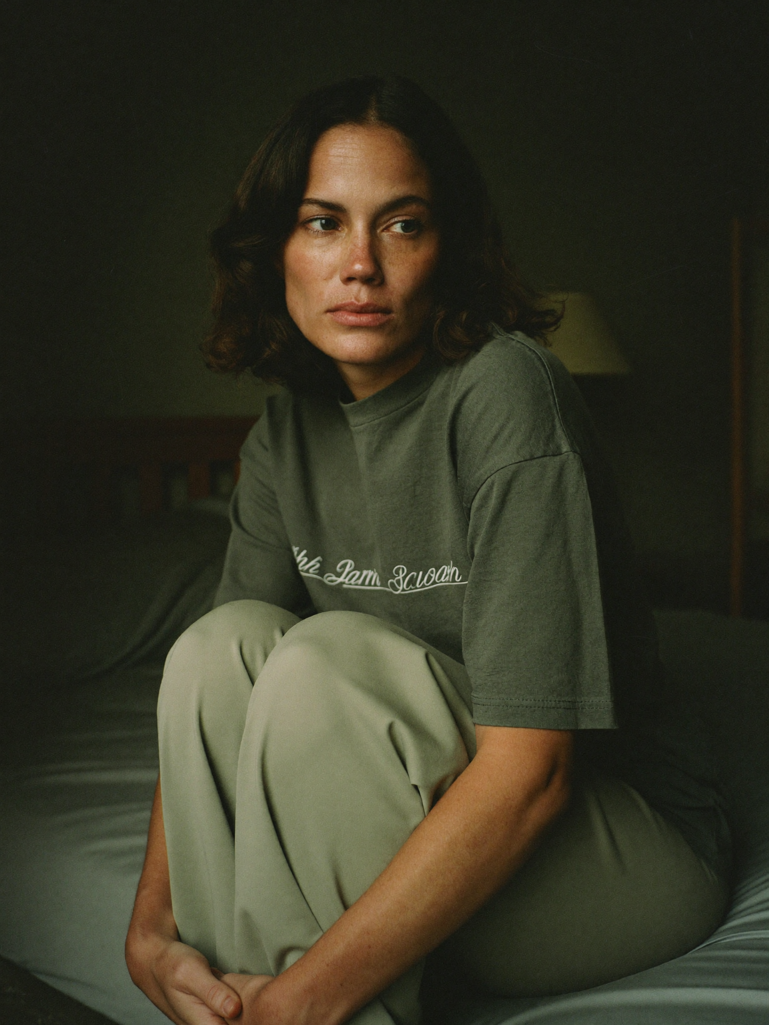 Sarah sitting on the edge of her bed at dawn, weighed down in thought