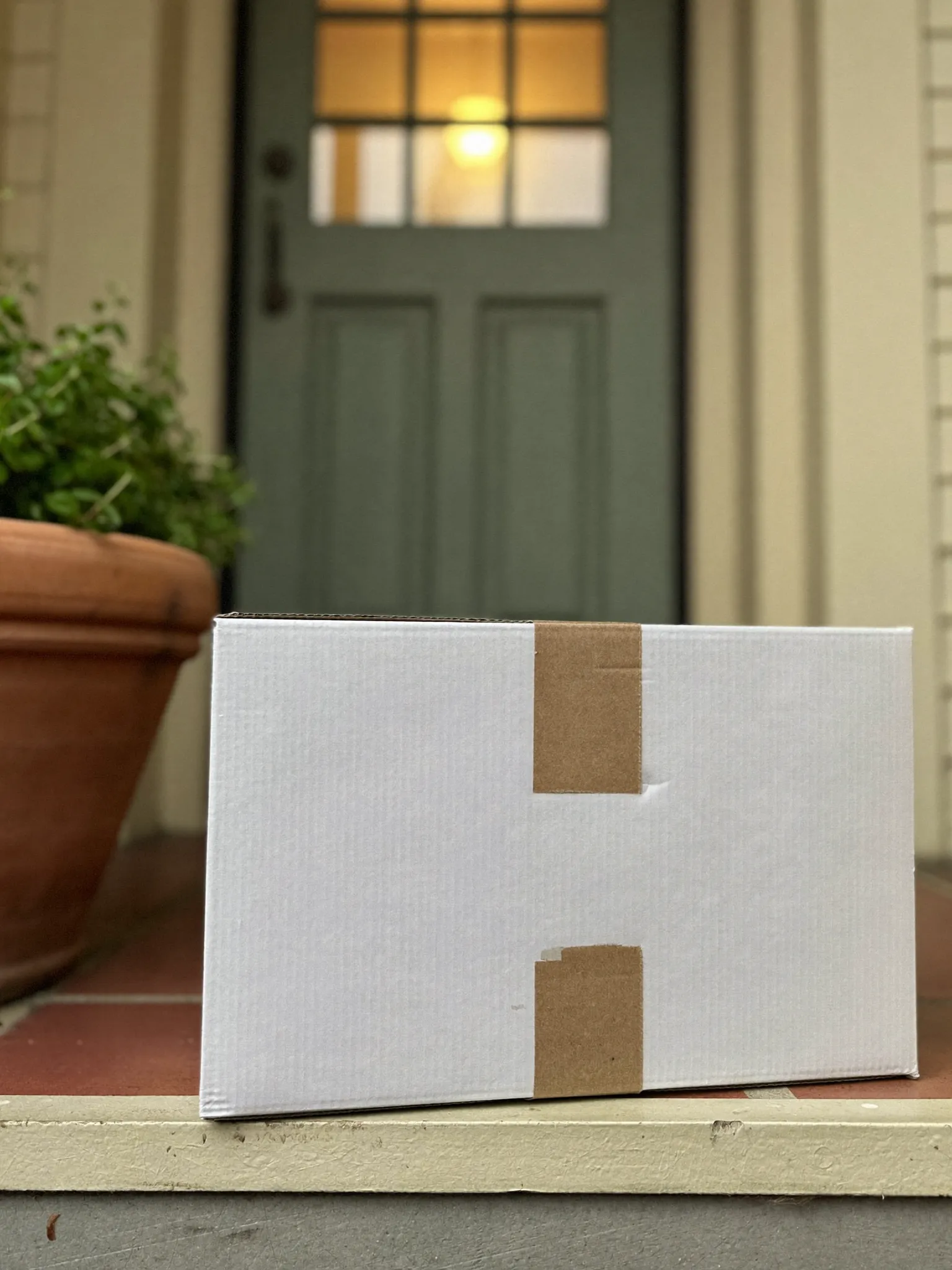 A plain unmarked delivery box on a doorstep in morning light