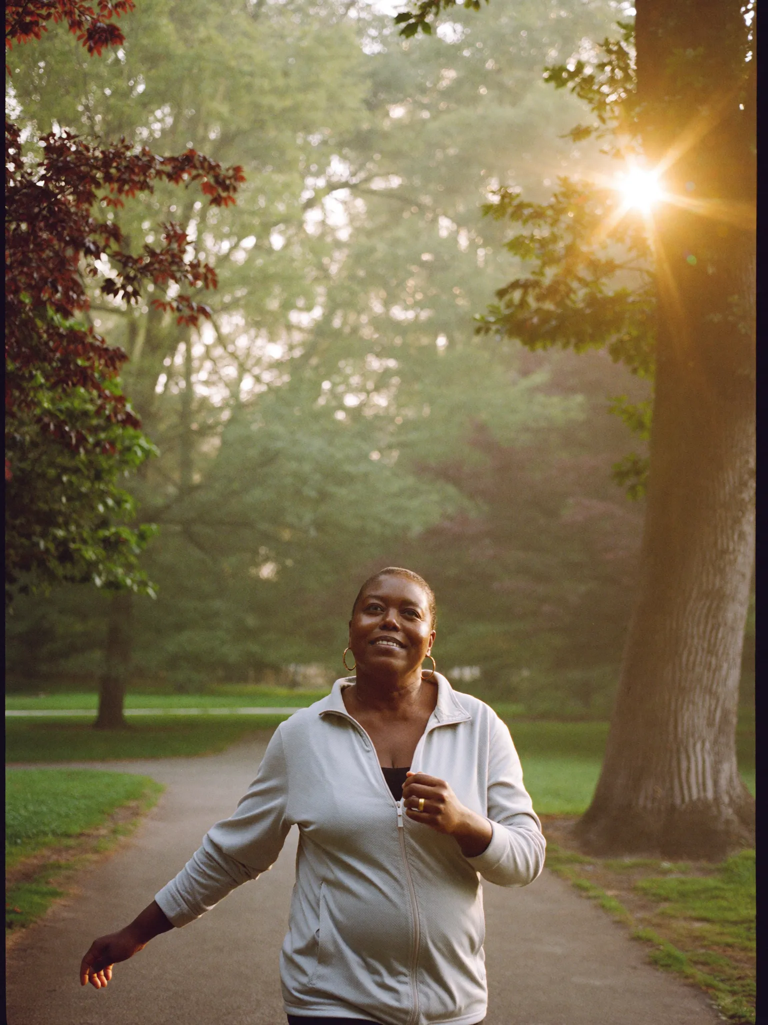 A woman walking through a park at golden morning light, at ease